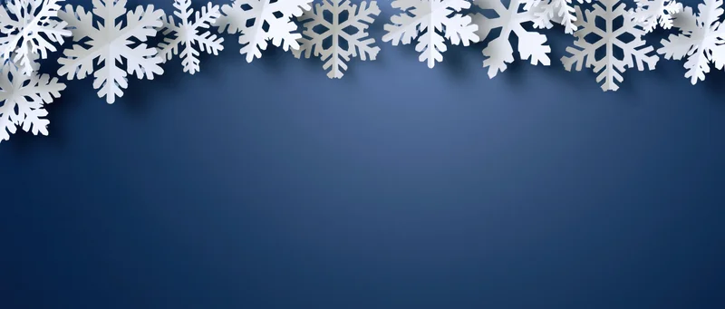 White paper snowflakes arranged along the top edge of a blue background with copyspace below