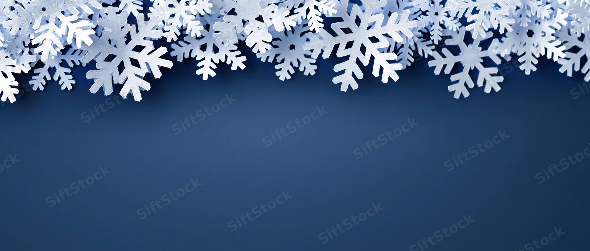 White snowflake decorations arranged as a border across the top of a blue background