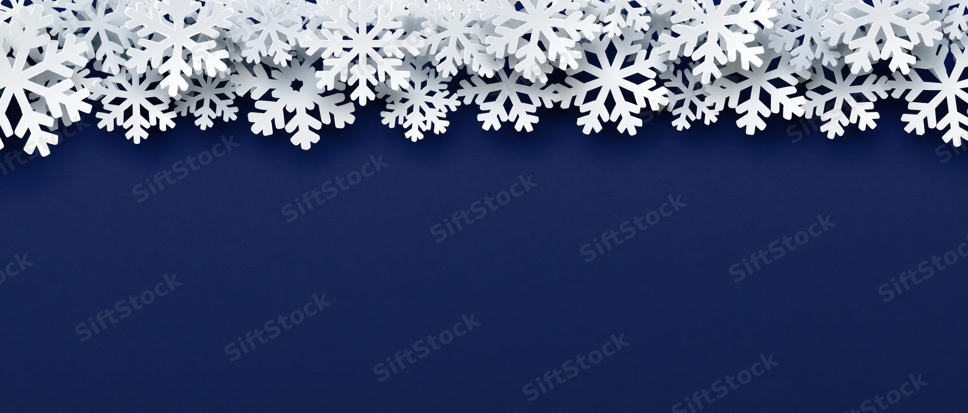 White paper snowflakes arranged as a decorative border along the top of a dark blue background with copyspace below