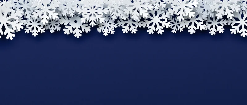 White paper snowflakes arranged as a decorative border along the top of a dark blue background with copyspace below