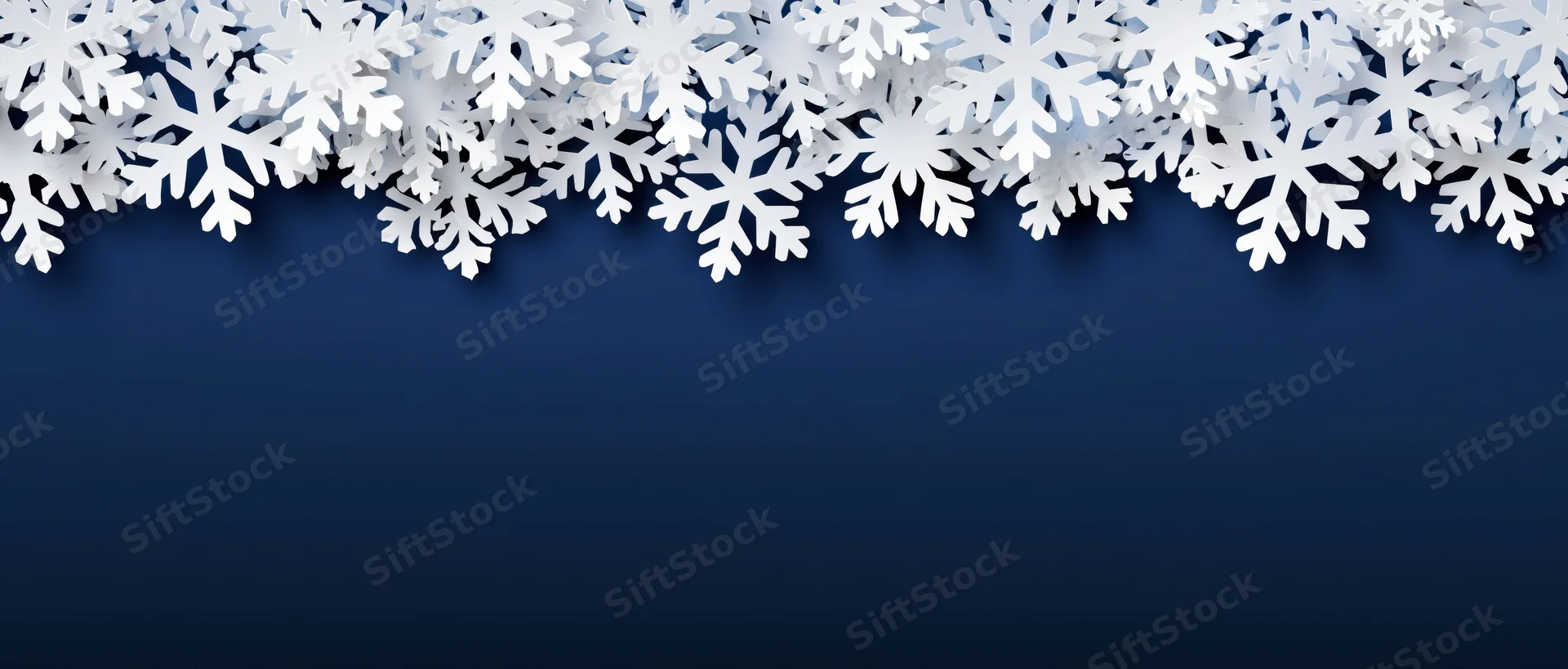 White paper snowflakes arranged as a decorative border along the top of a dark blue background with copyspace below