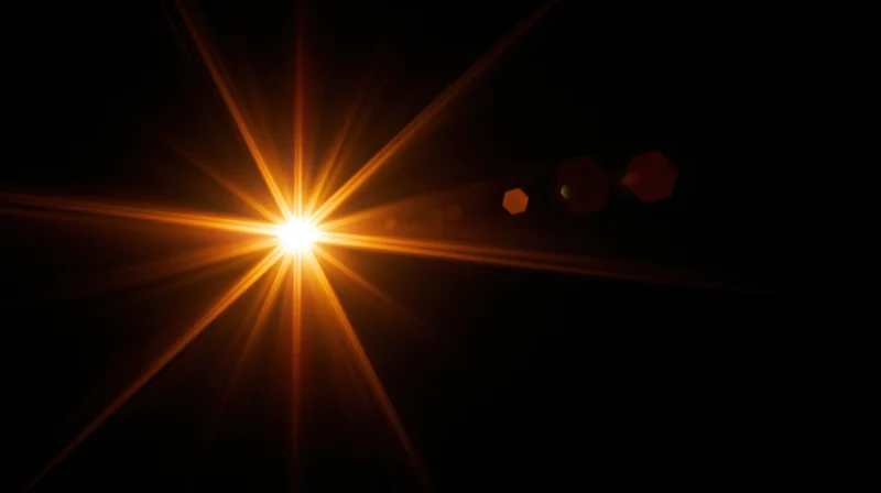 Bright orange starburst light flare on black background with lens flare artifacts