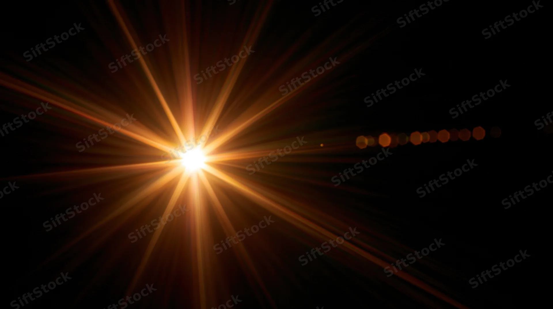 Bright starburst light flare radiating from center against black background with bokeh circles to the side