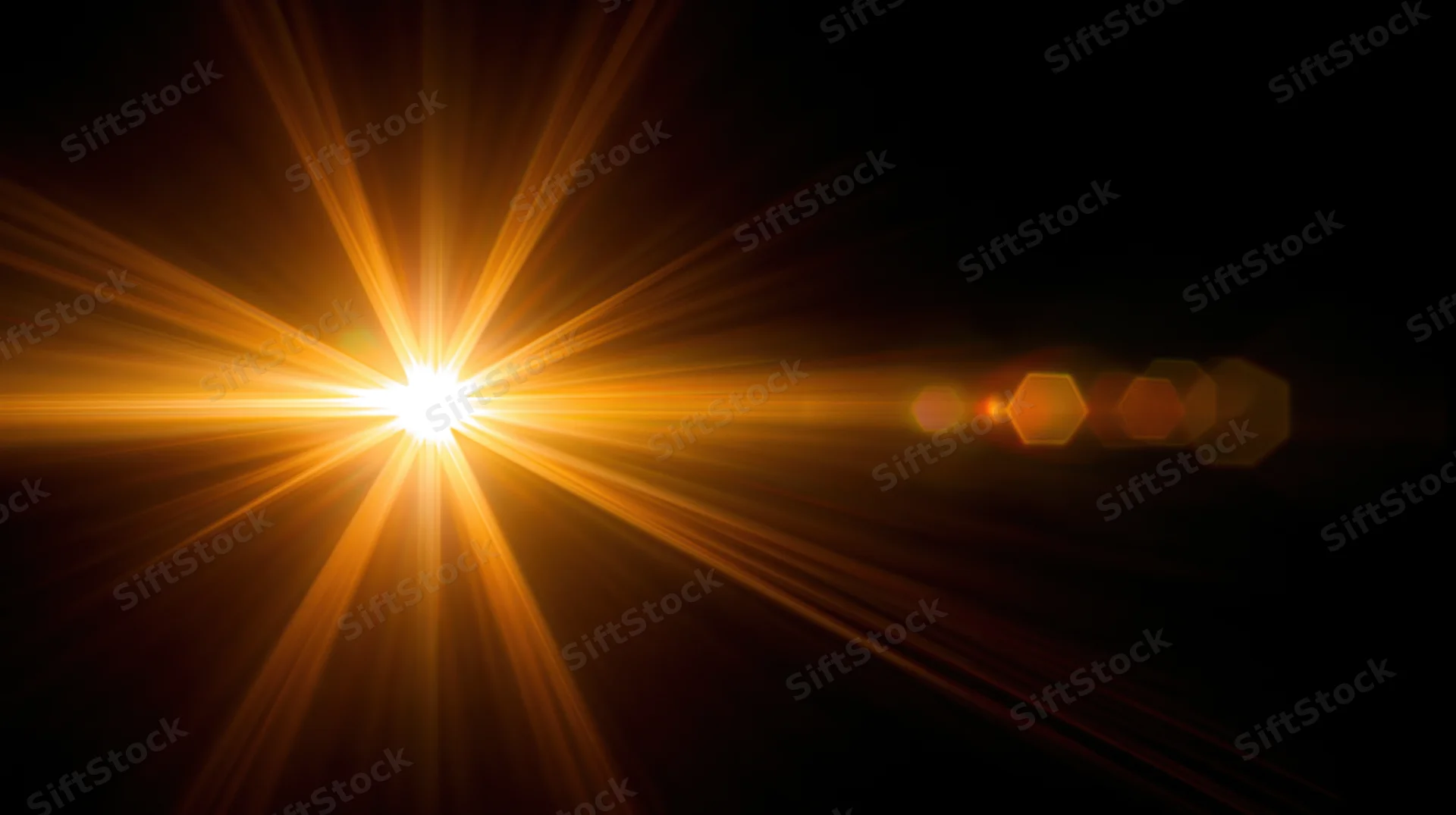 Bright golden light burst with lens flare and hexagonal bokeh against dark background