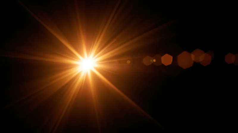 Bright golden light burst with lens flare and hexagonal bokeh against dark background