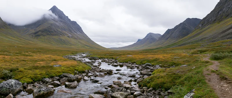 Mountain Valley Landscape with a Meandering Stream Under Clo