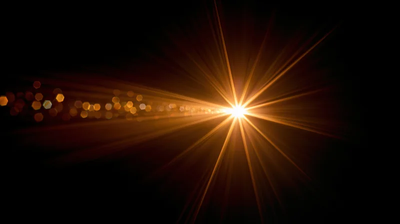 Bright golden light burst radiating from center against dark background with bokeh lights and copyspace