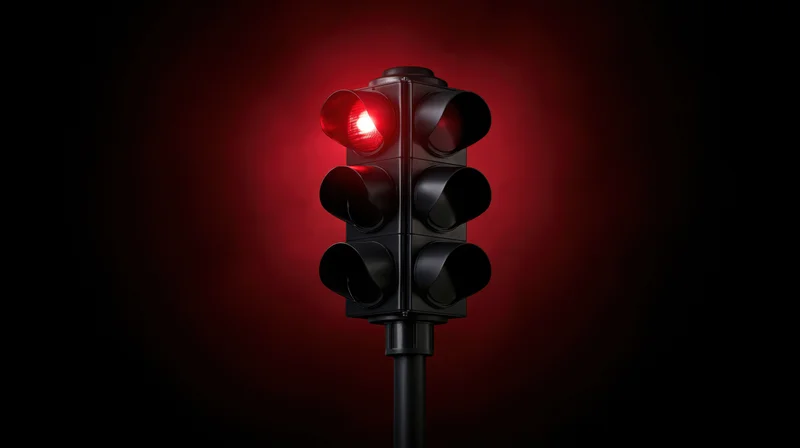 Traffic light with red signal illuminated against dark background