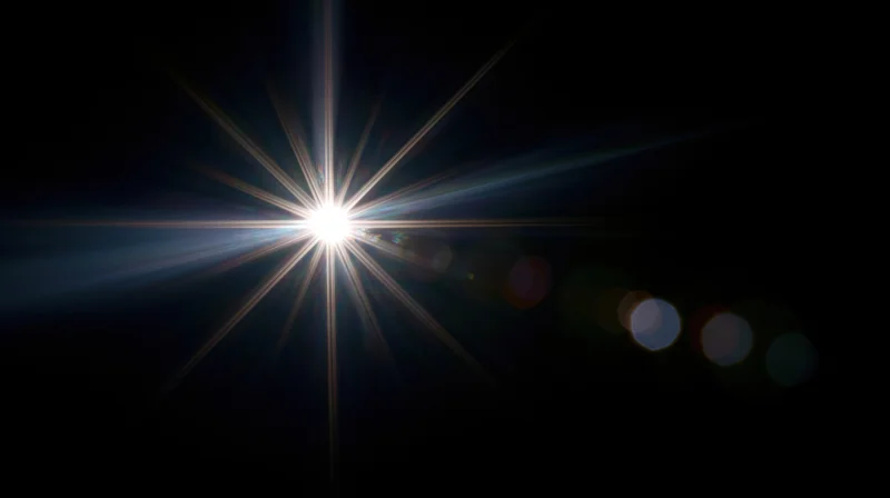 Bright starburst light flare with bokeh highlights on dark background