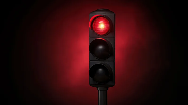 Vertical traffic light with red signal illuminated against dark background