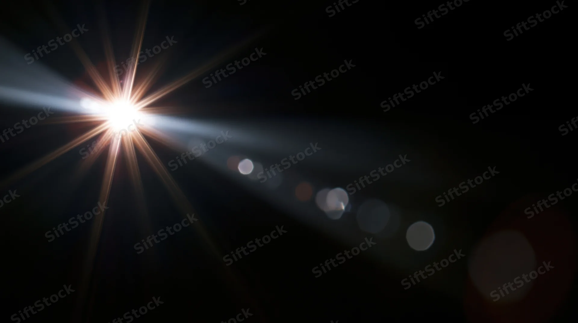 Bright light source creating starburst flare and bokeh circles against dark background