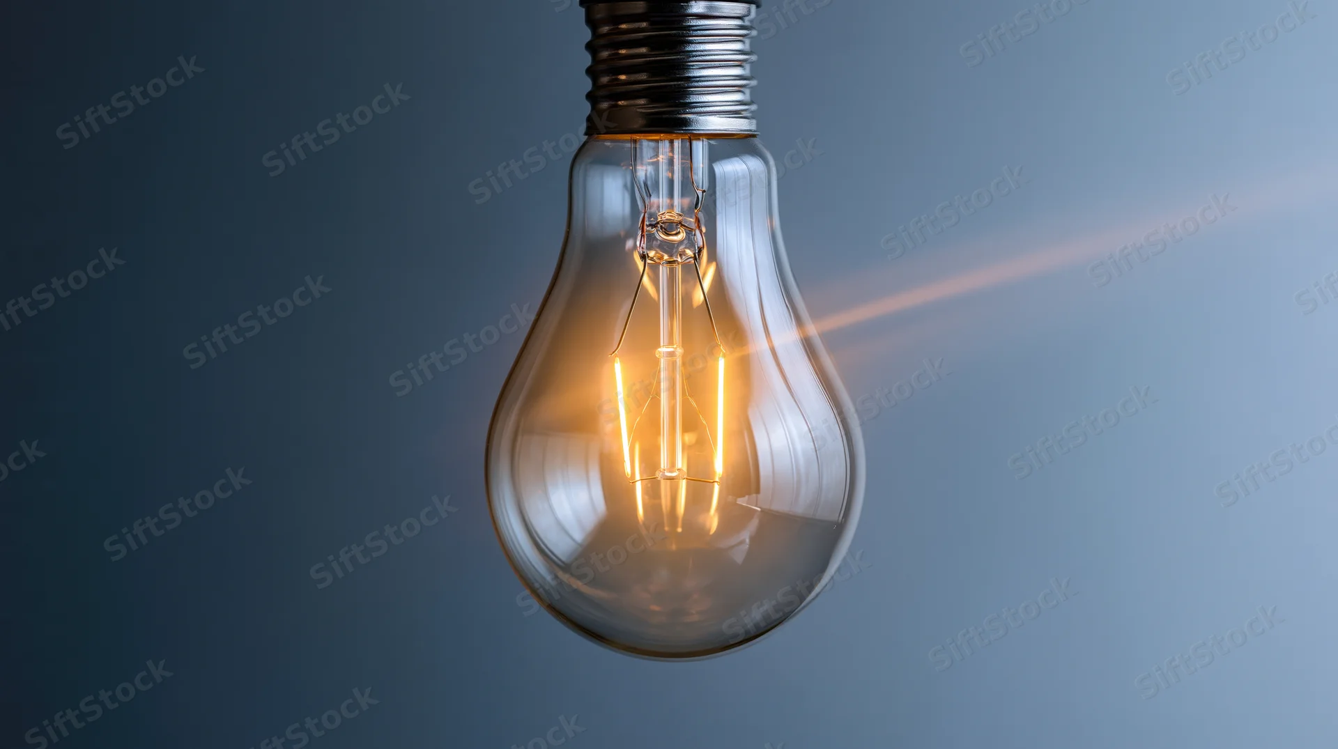 Glowing incandescent lightbulb with visible filament suspended against a gradient blue background