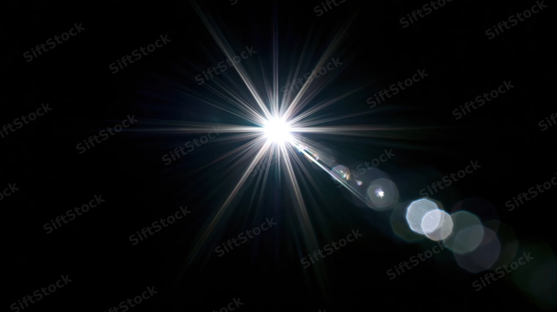 Bright starburst light flare with bokeh circles on black background