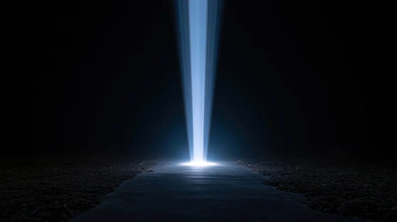 A bright blue light beam shining down onto a dark path at night