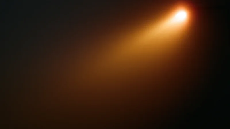 A spotlight beam glowing warmly in a dark space, casting a diagonal light gradient across the frame