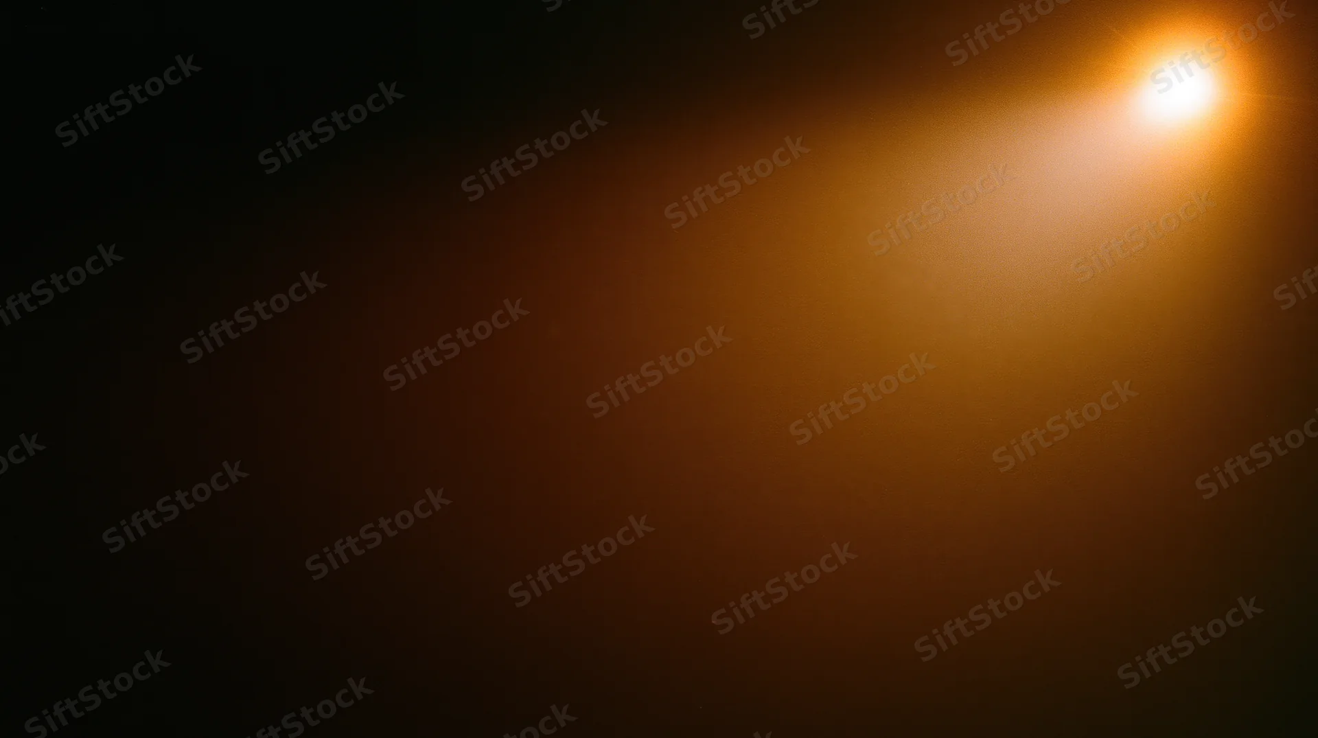 A bright warm light glowing in a dark hazy space with soft radiance and copyspace