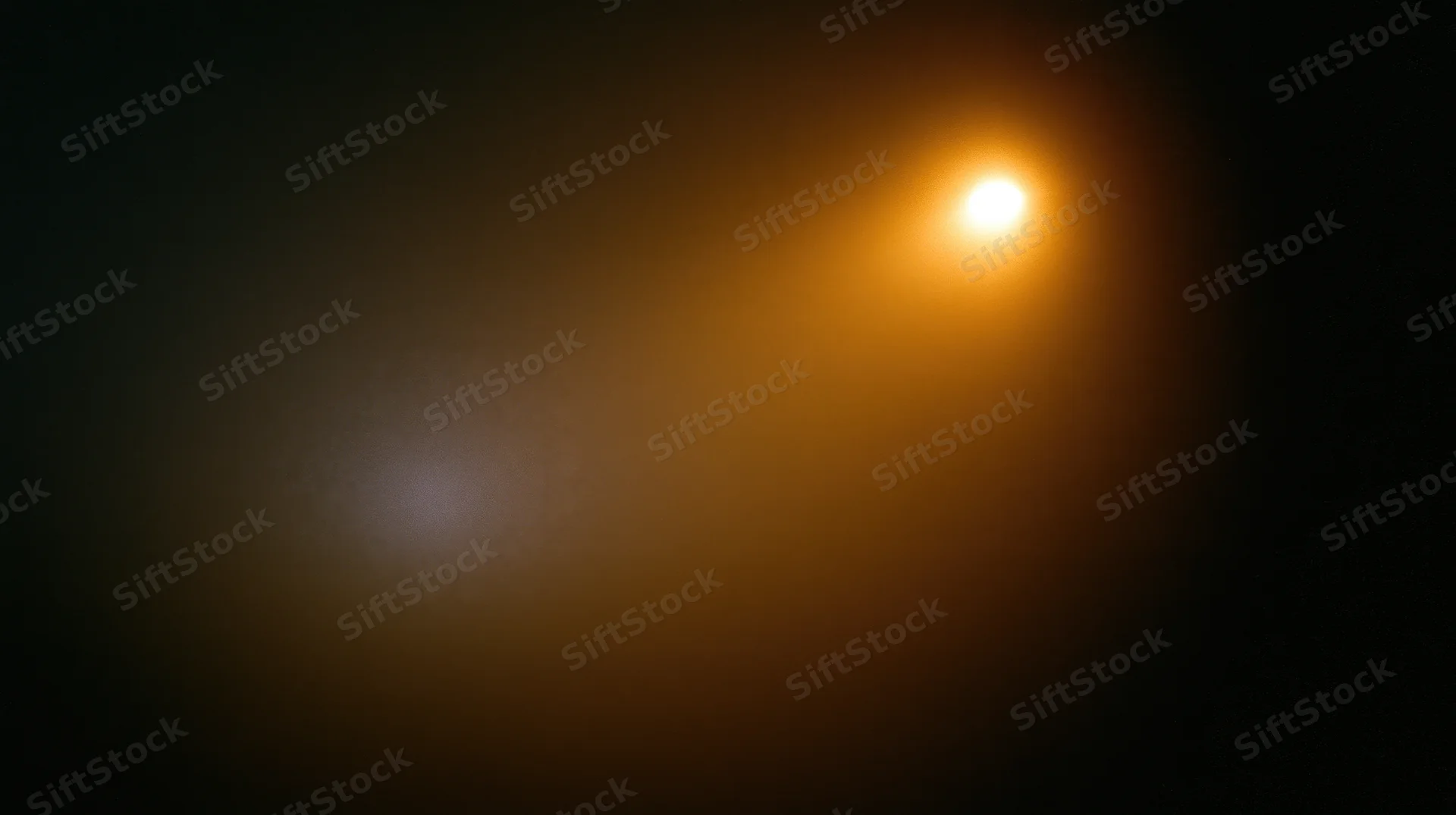 A bright orange light glowing softly in a dark space with warm ambient radiance and blurred background