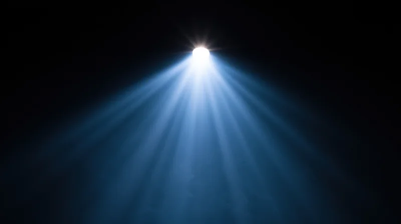 Spotlight beam shining down from above in a dark space