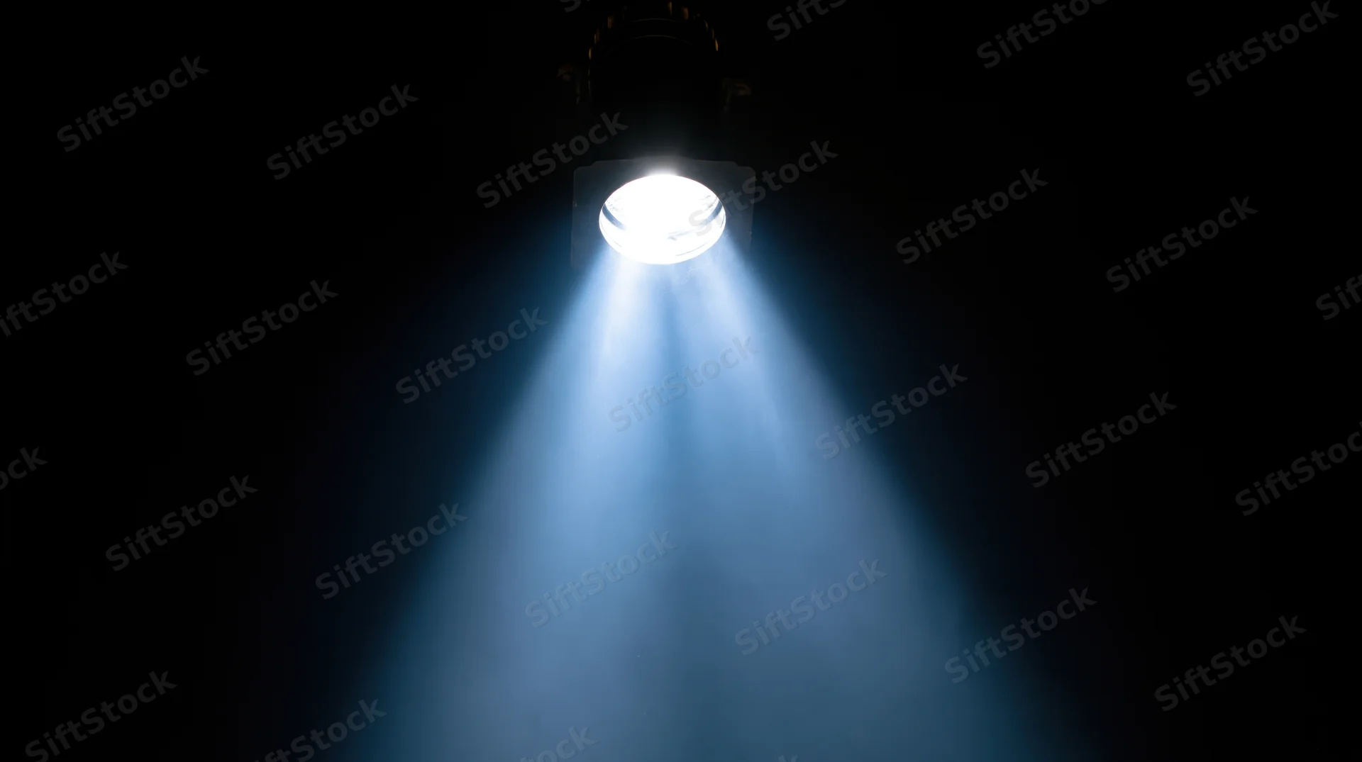 Spotlight beam shining down from ceiling in dark theater setting