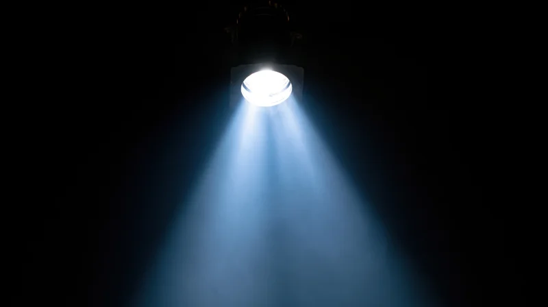 Spotlight beam shining down from ceiling in dark theater setting