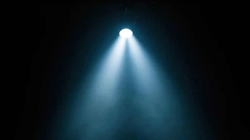 Spotlight beam shining down on dark stage with blue haze