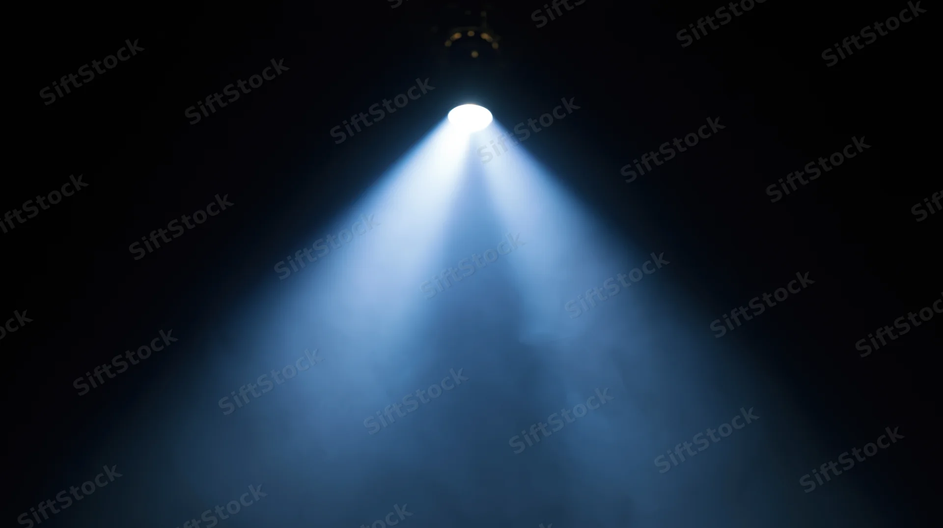 Spotlight beam shining down through smoke on a dark stage