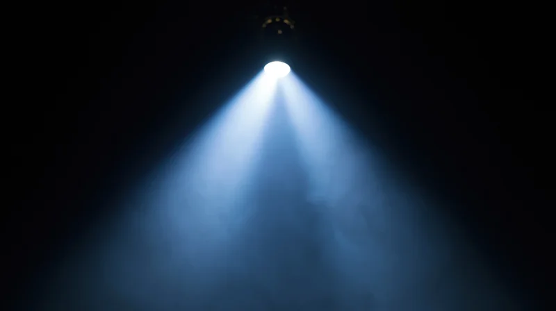 Spotlight beam shining down through smoke on a dark stage