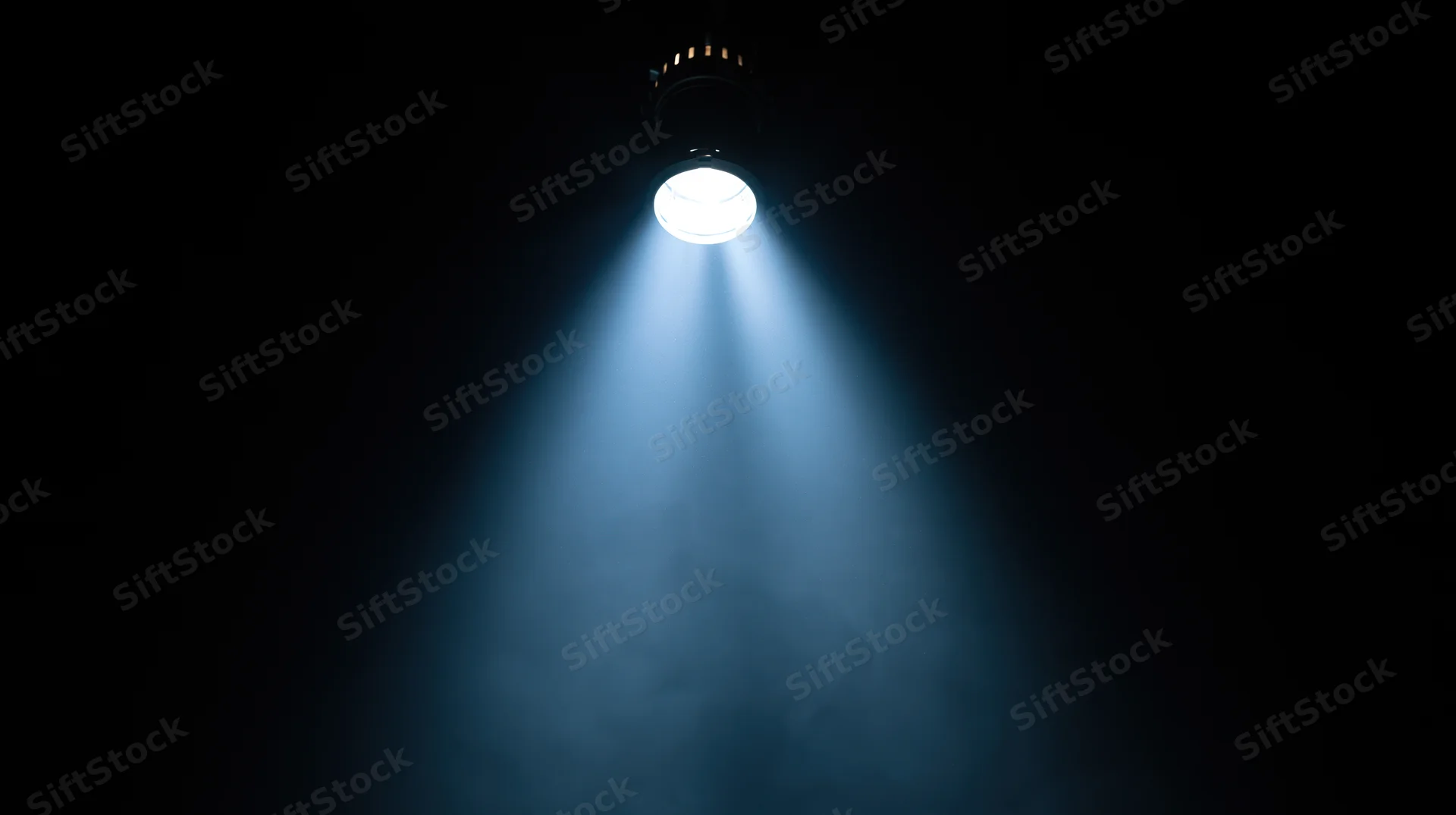 Spotlight beam shining down through smoke in a dark theater space
