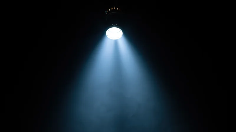 Spotlight beam shining down through smoke in a dark theater space