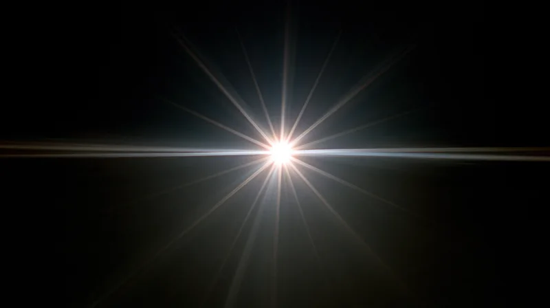 Bright light source emitting starburst rays across dark background