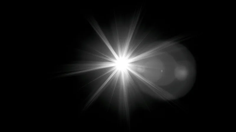 Bright starburst light flare on black background with copyspace