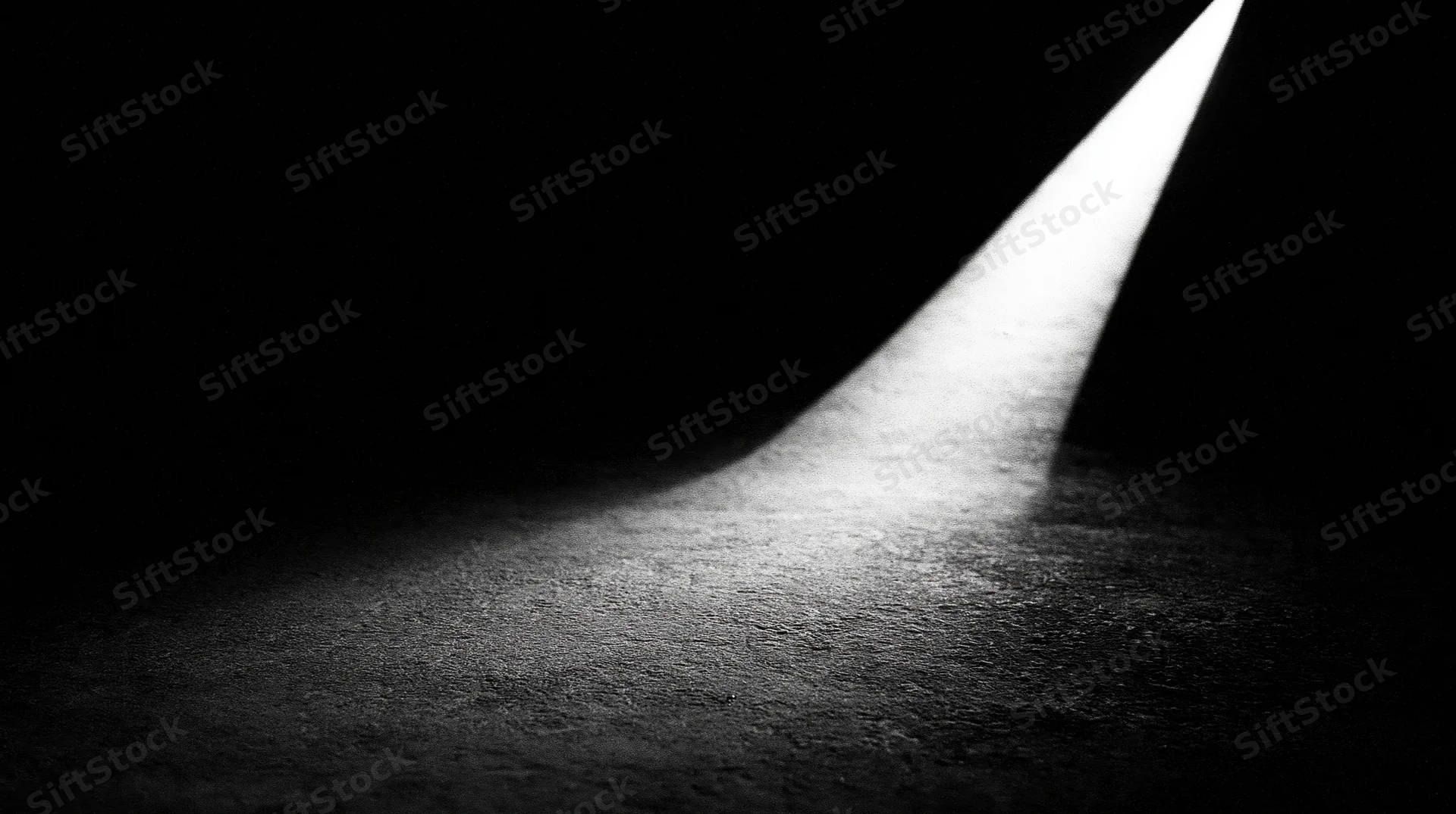 A beam of light cutting through darkness on a textured floor
