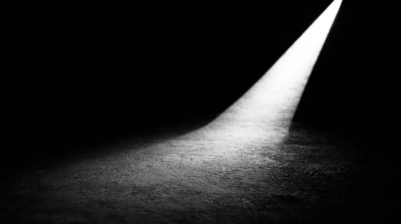 A beam of light cutting through darkness on a textured floor