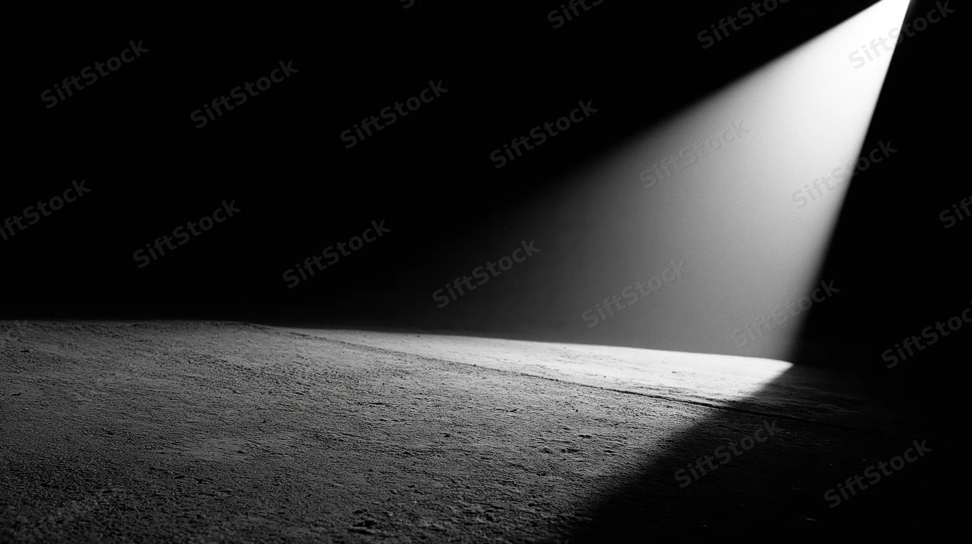 A beam of light cutting across a dark concrete floor in an empty interior space