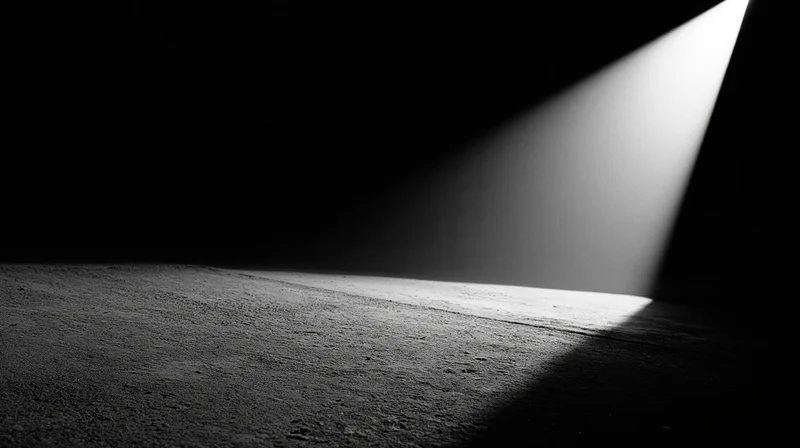 A beam of light cutting across a dark concrete floor in an empty interior space