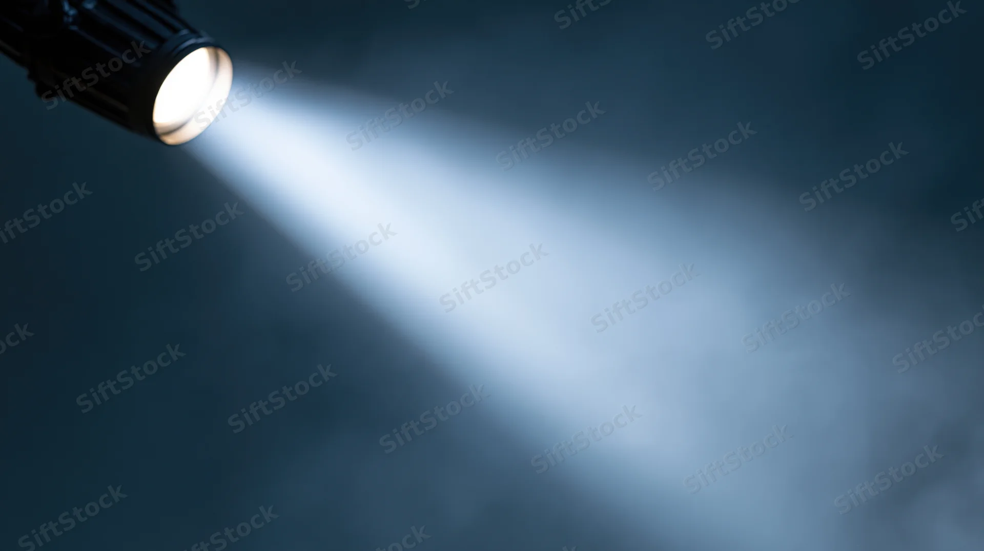 Spotlight beam cutting through dark smoky air in theater setting