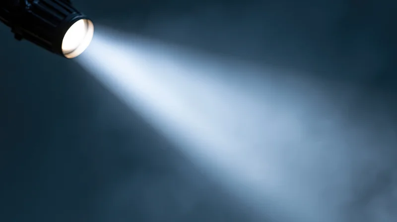Spotlight beam cutting through dark smoky air in theater setting