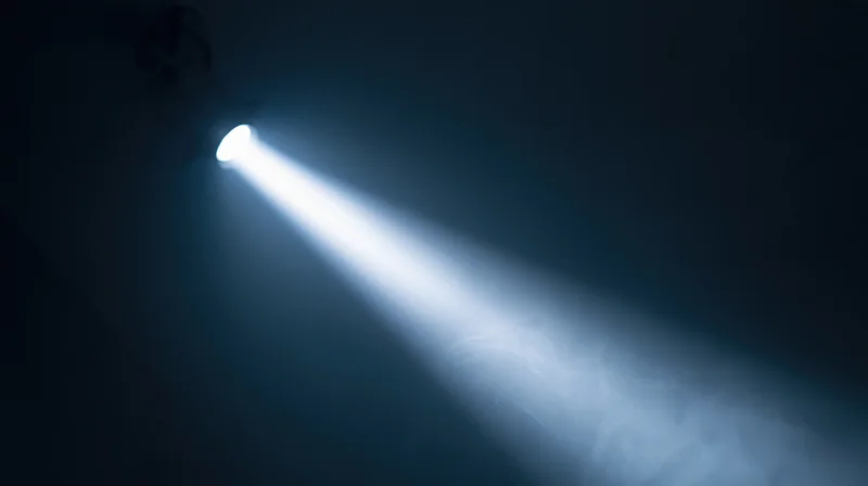 Spotlight beam cutting through dark smoky air in theater setting