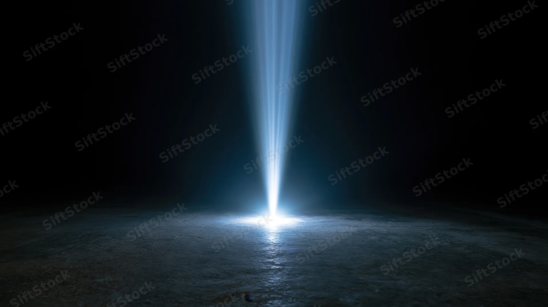 A spotlight beam illuminating a dark concrete floor at night