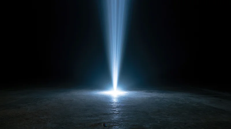 A spotlight beam illuminating a dark concrete floor at night