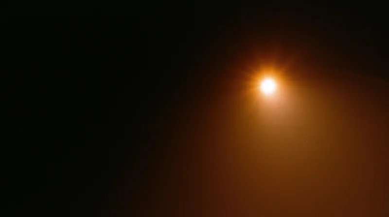 Bright orange streetlight glowing in dark night sky with hazy atmosphere and copyspace on left side