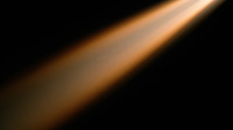 Diagonal beam of warm orange light across dark background with soft glow and gradient intensity
