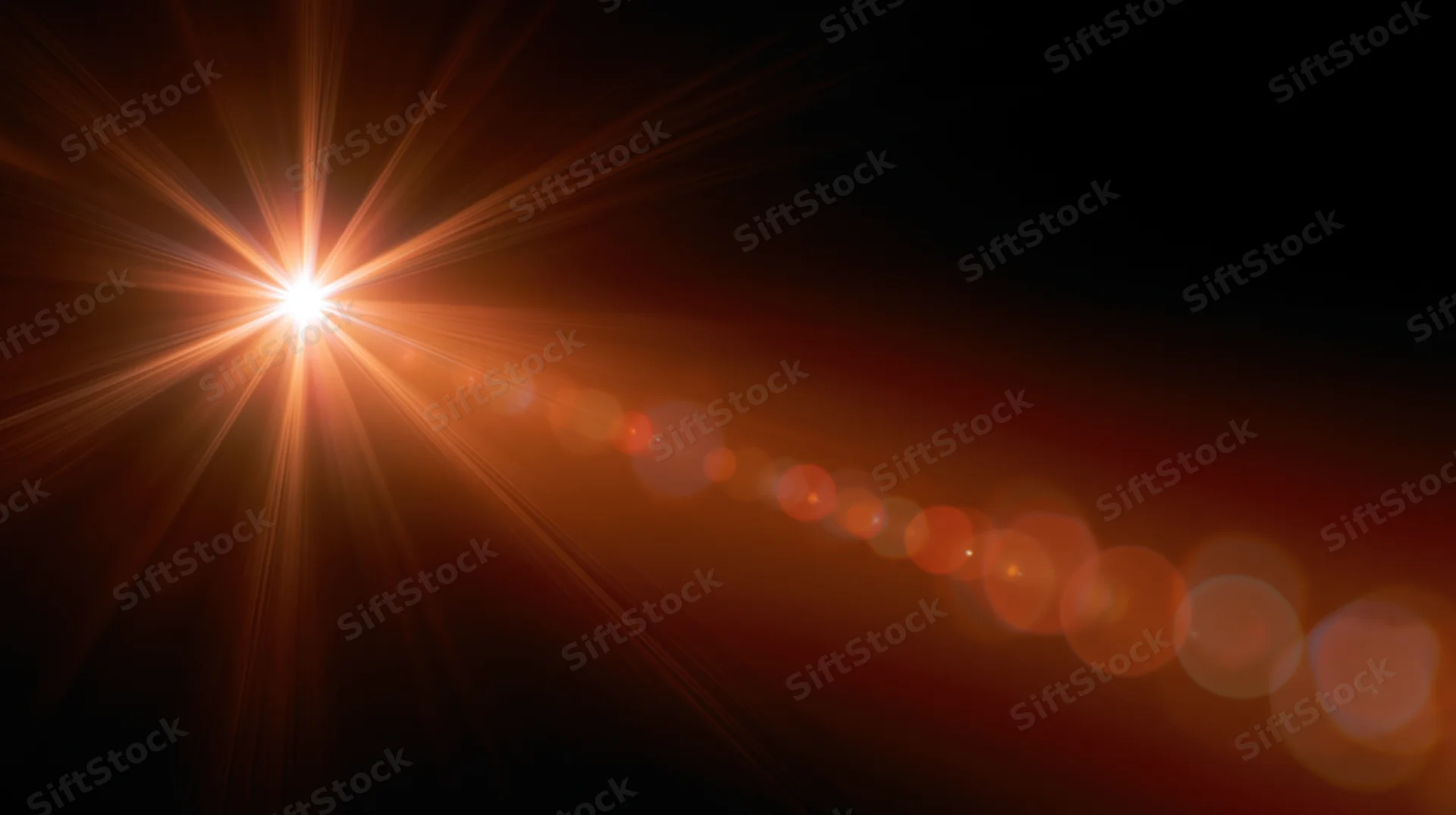 Bright orange starburst light flare with bokeh circles on dark background