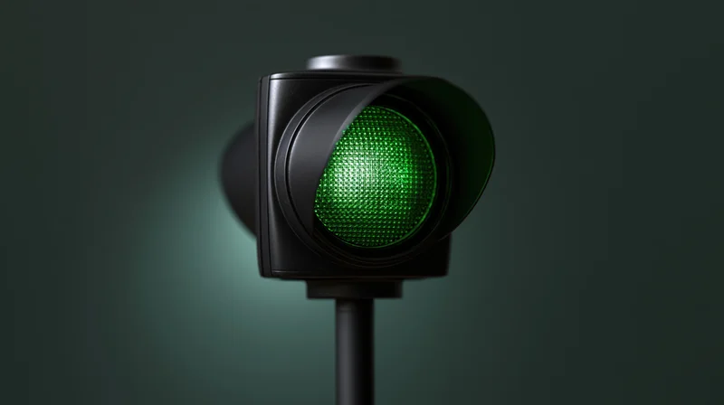 Green traffic light illuminated on a pole against a dark background