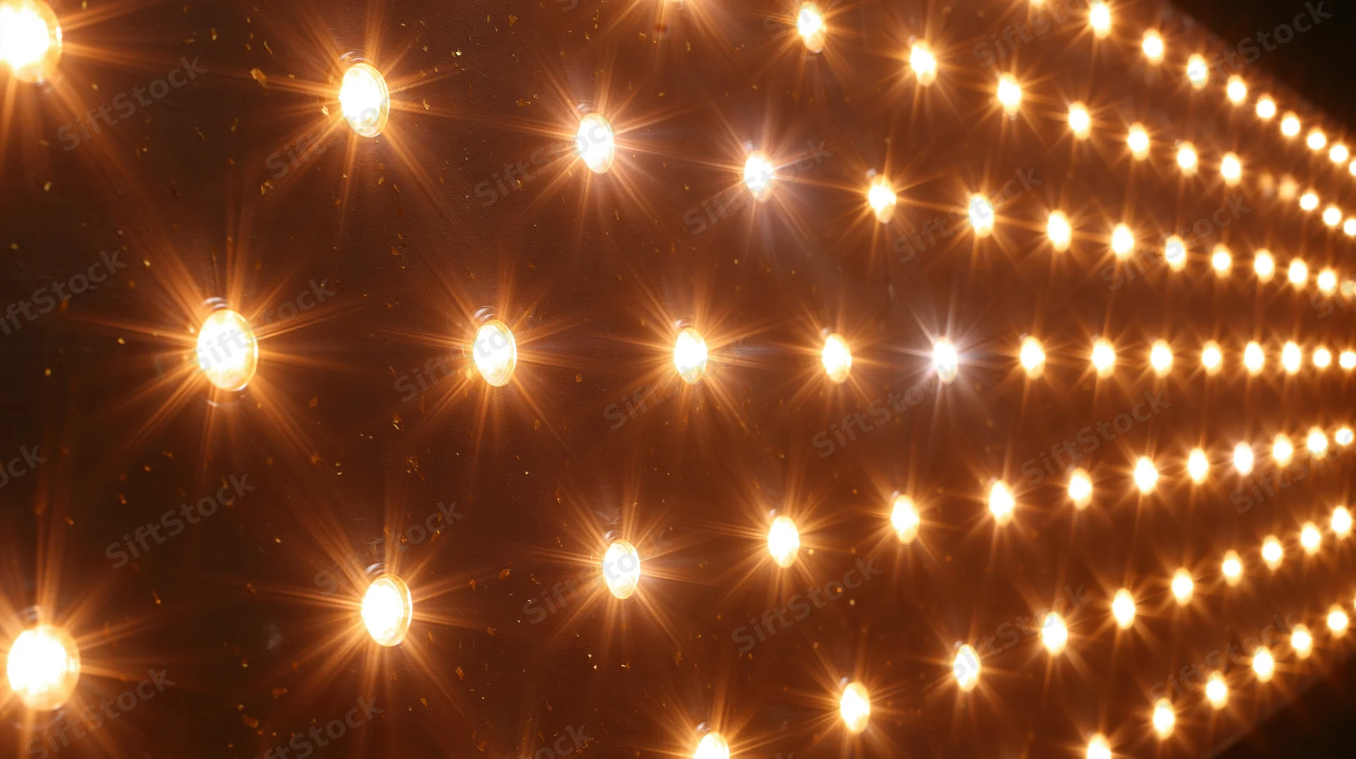 Rows of glowing lightbulbs arranged in a grid pattern on a dark surface