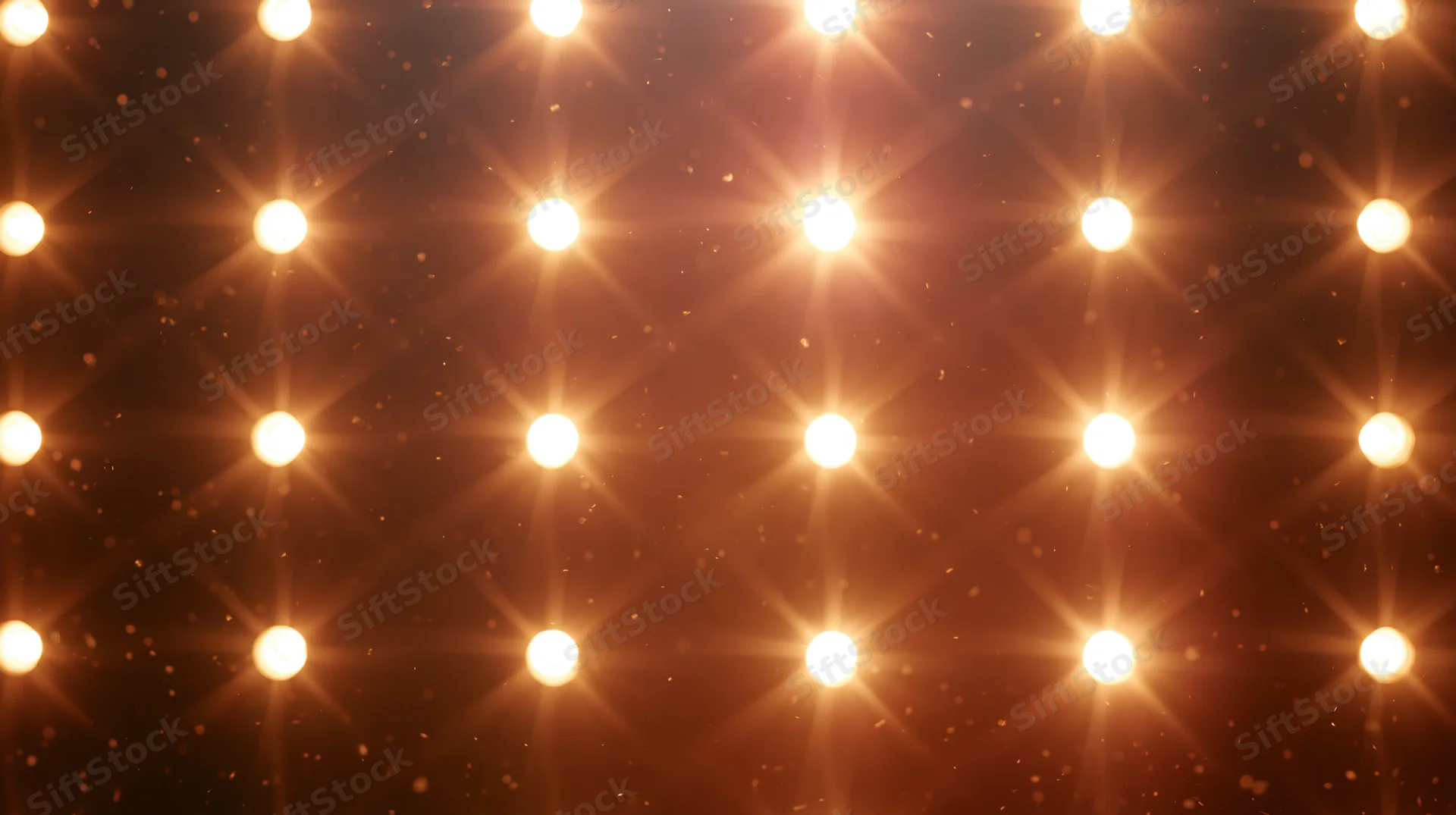 Grid of warm glowing stage lights arranged in rows against a dark background with sparkling particles