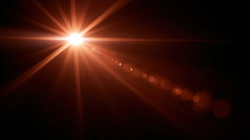 Bright light source emitting starburst rays and bokeh circles against dark background