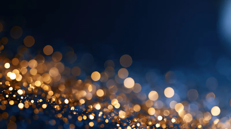 Golden bokeh lights scattered across a dark blue background with soft glow and festive sparkle