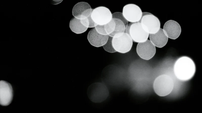 Blurred circular lights glowing against a dark background in monochrome