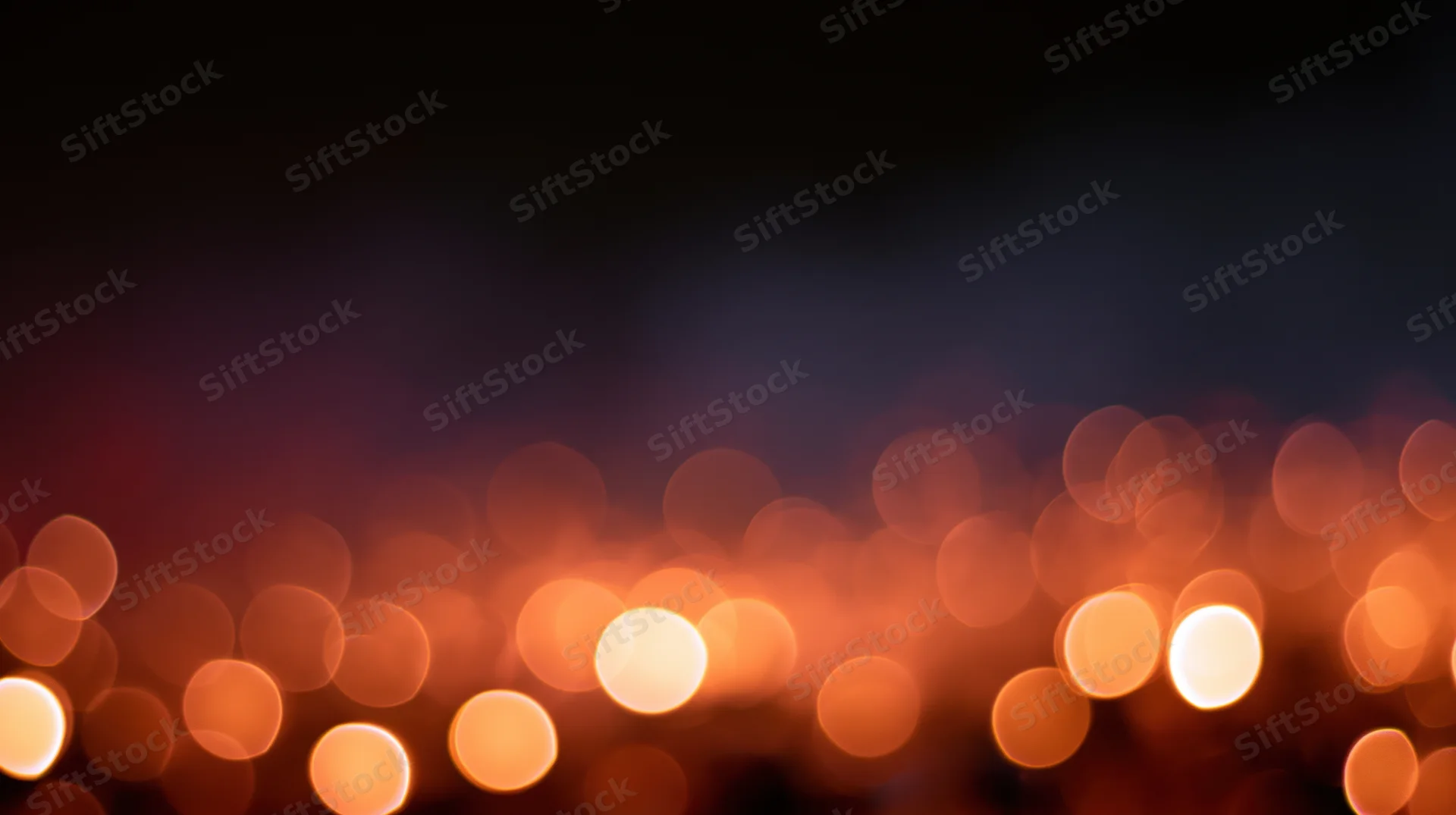 Blurred orange bokeh lights arranged horizontally against a dark background with copyspace above